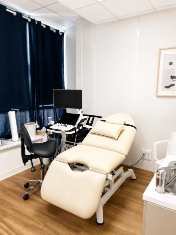 Photo du centre d'une salle de consultation au centre de santé de Roubaix, avec une table d'examen blanche et un échographe