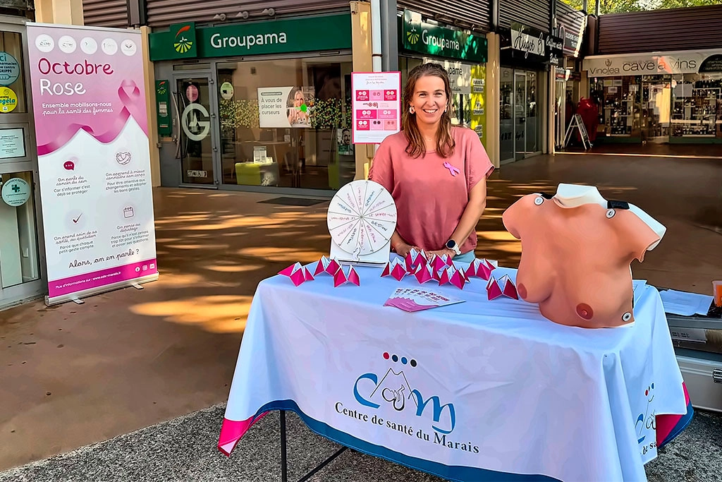 Photo du Dr Capucine Mangin au stand Octobre Rose des centres de santé du Marais présent à l'université Savoir Mont Blanc près de Chambéry. Elle présente aux étudiants un buste pour montrer les gestes d'autopalpation.